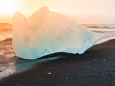 冰岛Jokulsarlon冰川湖附近日出时黑沙滩的海浪使冰山崩裂海洋气候日落旅行波浪太阳戏剧性火山花饰冰川图片