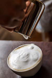 男人倒在一杯咖啡里 里面有奶汁房子牛奶拿铁服务店铺咖啡师女性艺术酒吧美食图片