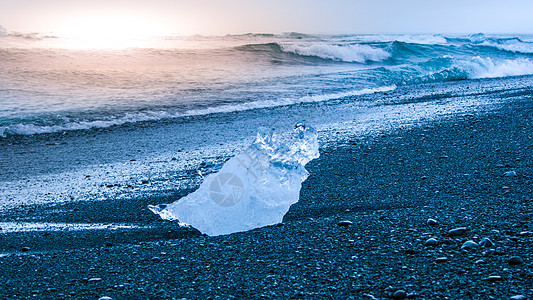 冰岛Jokulsarlon冰川湖附近日出时黑沙滩的海浪使冰山崩裂花饰海洋戏剧性蓝色气候海岸太阳水晶天空旅行图片