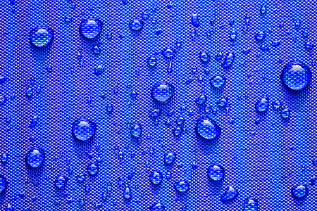 在蓝色防水布 backg 上特写水滴图案纺织品涂层雨滴宏观水晶季节液体流动纤维衣服图片