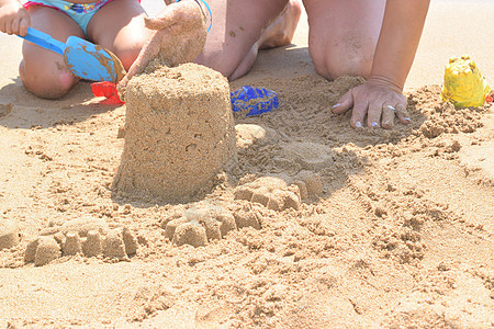 在海滩上建沙滩城堡母亲儿子童年蓝色男生海岸乐趣闲暇假期建筑图片
