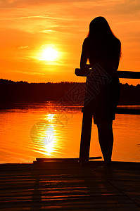 站在码头上的年轻女子的日落光影图片