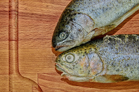 木板上的两条生虹鳟鱼 健康的食物和饮食概念 增加暗色对比度图片