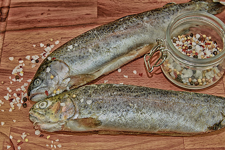 两条生彩虹鳟鱼 木板上配有香料 健康食物和饮食概念 增加暗反差图片
