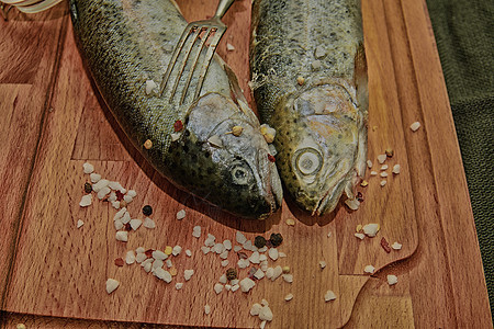 带香料和木板叉子的新鲜新生虹鳟鱼 健康食物和饮食概念 特写 增加暗色对比度图片