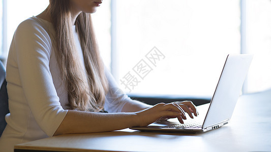 在大窗口前的笔记本电脑键盘上贴近女性手打字图像成人办公室衬衫技术购物商业铅笔桌子窗户工作背景图片