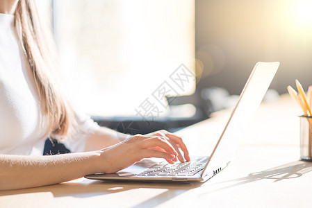在大窗口前的笔记本电脑键盘上贴近女性手打字图像工作购物商业衬衫职场耀斑窗户铅笔人士桌子图片
