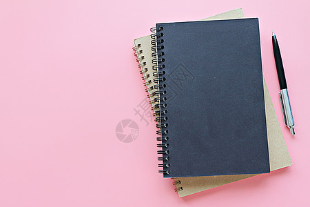粉红色背景上的笔记本和笔的顶部视图或平整版记事本软垫学校工作商业植物日记笔记生活办公室图片