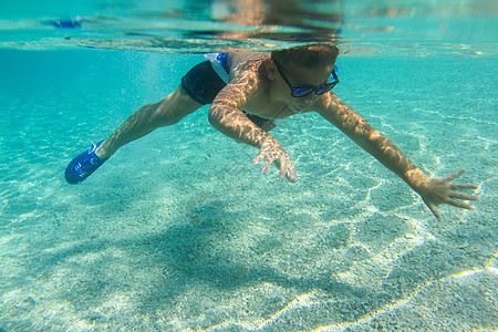 男孩在水下游泳呼吸管海滩热带潜水娱乐蓝色太阳镜闲暇乐趣假期图片