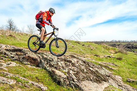 红夹克骑马山下落基山 极端运动和冒险概念的赛车手岩石天空成人踪迹下坡娱乐乐趣行动运动员竞赛图片