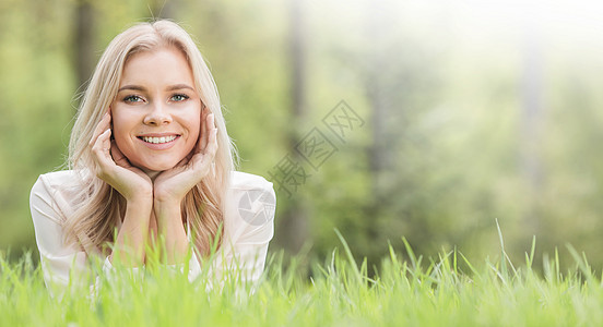 美丽的女孩躺在草地上享受闲暇金发场地公园微笑喜悦乐趣成人女性图片