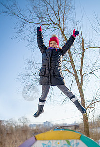 女童在冬季跳跃喜悦天空青少年衣服女性乐趣女孩蓝色微笑帽子图片