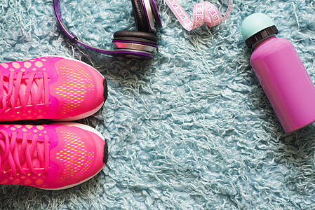 粉色运动鞋 仪表 水瓶和耳机放在毛地毯上 在健身室背景中 用于运动和锻炼的辅助设备图片