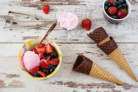 粉色冰淇淋配浆果黄色碗中的草莓和蓝莓 巧克力蛋筒华夫饼 浅色质朴的木制背景水果巧克力食物胡扯味道产品宏观牛奶勺子奶制品图片