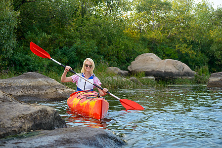 青春女子在美丽的河边或湖边 在夜晚的石头中间银行划桨娱乐假期探索工作运动员运输女性旅行图片