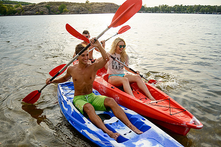 朋友在美丽的河流或日落湖上玩着Kayaks蓝色闲暇日落运动男人乐趣女士划桨旅行冒险图片