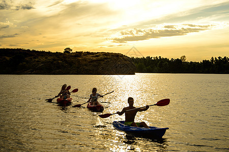 日落时 朋友们在美丽的河流或湖泊上划着皮划艇 在壮观的夜空下女士闲暇晴天男人人群朋友旅游戏剧性探索假期图片