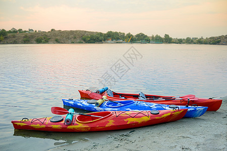 三人在美丽河附近沙滩或夜晚的湖边旅行Kayaks 旅行和冒险概念 笑声海岸探索晴天划桨运输假期蓝色运动闲暇森林图片