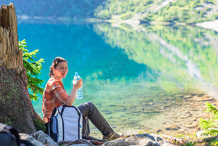 女人喝着一瓶饮用水 就在一个美丽的Sce附近图片