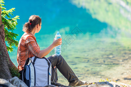 带着一瓶水的游客女孩 喜欢美丽的山地上奥科女士女性远足者眼睛蓝色国家踪迹树干公园图片