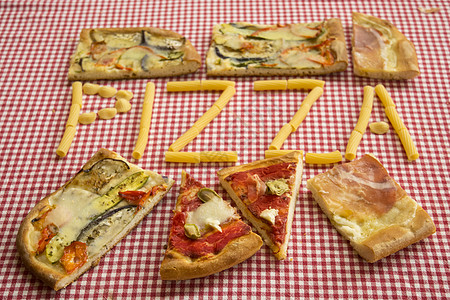 披萨片环绕着用意大利面做成的写作火腿素食主义者蔬菜图片