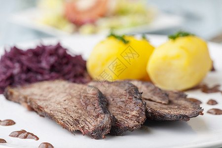 盘子上有红色卷心菜的德国sauerbraten烹饪美食肉汁叶子荒野水饺食物香菜沙拉蔬菜图片