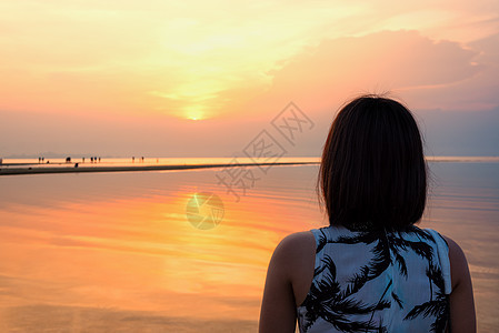 在海滩上看日落的女人热带假期天空橙子阳光风景日出旅行女孩女士图片