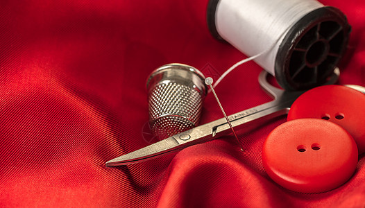 红色织物上的缝纫配件剪刀卷轴工具材料纽扣棉布裁缝维修按钮针线活图片