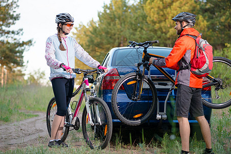 冒险与家庭旅行概念 由Bike Rack在汽车上搭乘的  年轻夫妇脱身山车安装男性耐力车轮车辆自行车头盔耐力赛男人女性图片