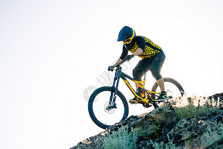 赛车手骑着山上摩托 在夏日落石轨的夜晚 极端运动和Enduro自行车概念乐趣活动冒险护目镜车轮天空下坡山地车男人男性图片
