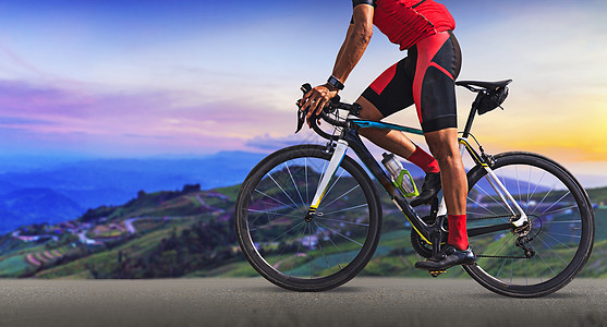 男人在美丽的山之间的一条路上骑着自行车娱乐运动速度下坡铁人成人男性行动头盔广告图片