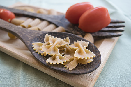 木板和新鲜西红柿上的全食意面蝴蝶木头钢包勺子柚子图片