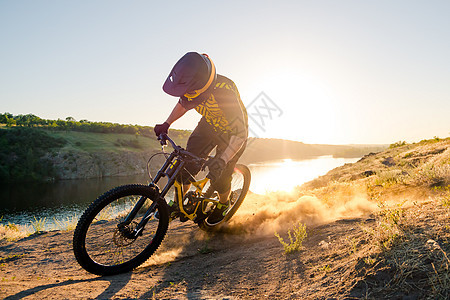 赛车手骑着山上摩托 在夏日落石轨的夜晚 极端运动和Enduro自行车概念耐力赛冒险男性山地车漂移下坡灰尘太阳眼镜活动图片