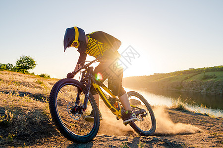 赛车手骑着山上摩托 在夏日落石轨的夜晚 极端运动和Enduro自行车概念踪迹车轮漂移下坡天空乐趣灰尘头盔男性骑士图片