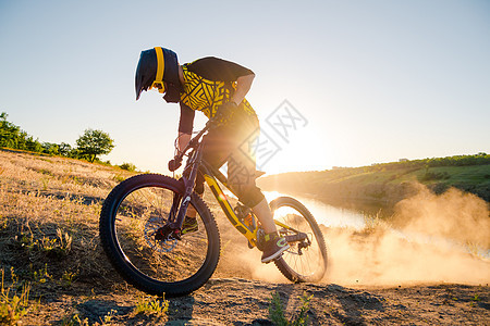 赛车手骑着山上摩托 在夏日落石轨的夜晚 极端运动和Enduro自行车概念灰尘太阳天空漂移男性护目镜冒险活动爬坡头盔图片