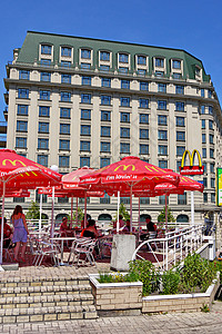 露台边的麦当劳咖啡厅 在城里一栋高房子的背景上挂着雨伞图片