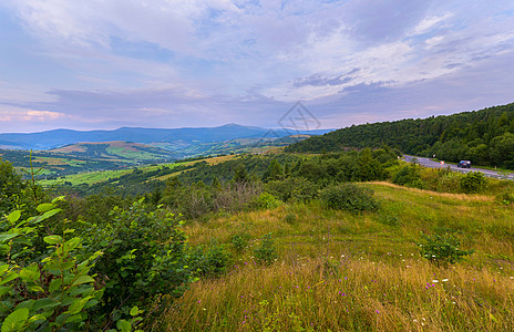 在遥远山丘背景的山谷上 一条直蓝车身旁的长尾小径图片