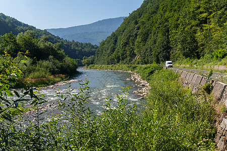 沿快河沿流河在高贵的绿色山脉背景下摇摇欲坠的道路图片