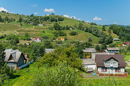 分散在一片绿草的山谷中的整洁农村房屋图片