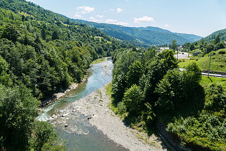 一条美丽而迅速的河流沿山脉流淌 充满绿树和灌木图片