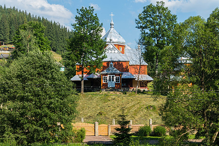 一个美丽的小木木教堂 屋顶和银穹顶 在一片绿森林和蓝天空的背面上图片