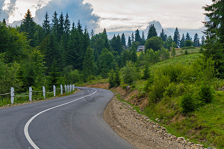 以青山为背景的道路有大量不同的植被和小农村房屋图片