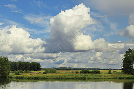 在美丽的云下河岸的田地上图片