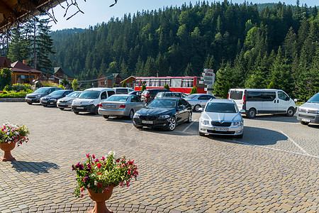 酒店附近的停车场停着名牌汽车 后面是旅游巴士 一切都位于山区 山坡上覆盖着茂密的森林图片