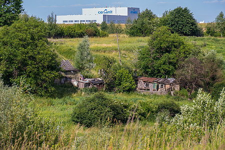 在一座庞大的工厂建筑的背景下 一个老旧农村房屋的废墟;图片