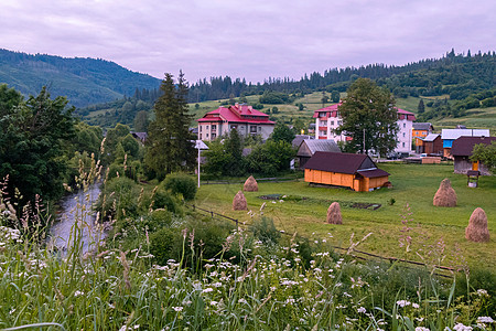 青山背景下一条小河道附近的红色屋顶和庭院高层住宅图片