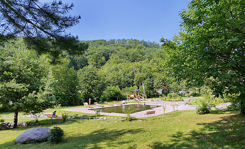 清洁泳池 配有木板凳 太阳休息员和公园区背景的游乐场图片