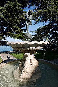 喷泉藏在绿色纤维下 雕塑着一个男孩拿着海豚的雕像图片