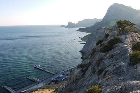 高山覆盖着青草的深山背景上的沿海陡峭悬崖图片