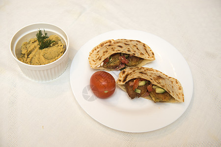 以色列流行的菜盘     白桌布上一块盘子中的falafel木板沙拉油炸小吃草药面包美食胡椒饮食蔬菜图片